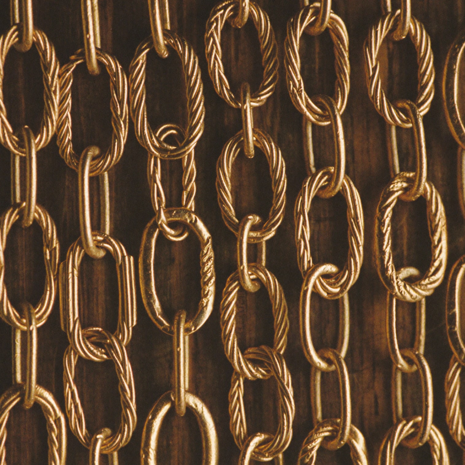 Macro detail of hand-drawn gold wire coiled into fine chain links.